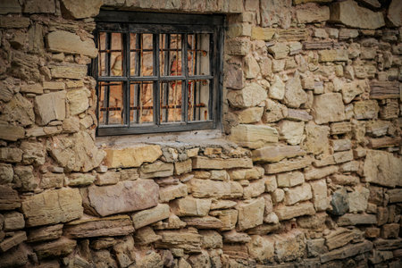 Old stone wall with a window and wooden lattice. Toned.の写真素材