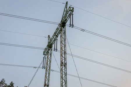 High voltage power lines and pylons against the blue sky.