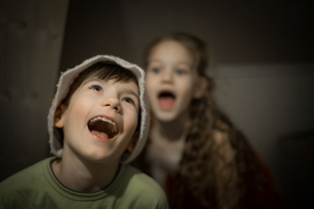 Two children, boy and girl, posing in the dark at homeの写真素材