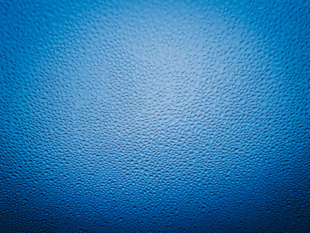 Water drops on window glass with blue tone. Abstract background and texture for design.の写真素材