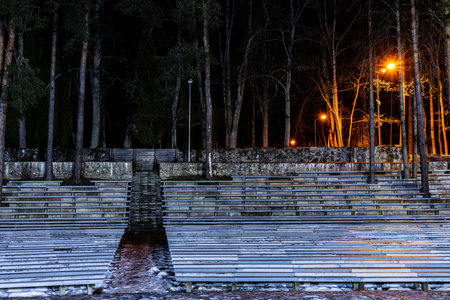Wooden benches on the shore of the lake in the park at nightの写真素材