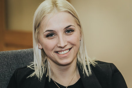 portrait of a beautiful young blond woman in a black jacket on a gray backgroundの写真素材