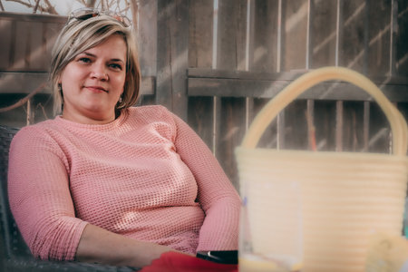 A woman in a pink sweater sits in a cafe and drinks coffee.の写真素材