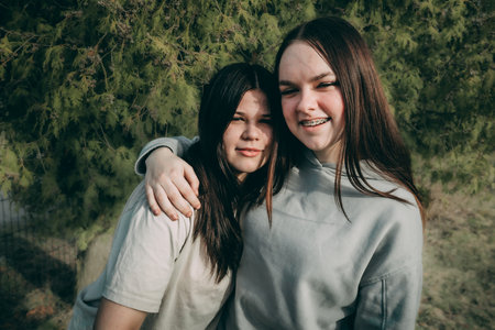 Two beautiful young women hugging each other in the park. The girls are smiling.の写真素材