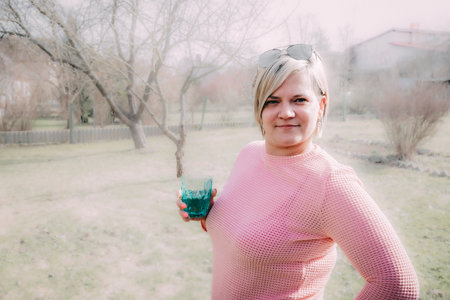 Portrait of a middle-aged woman in a pink sweater with a glass of water.の写真素材