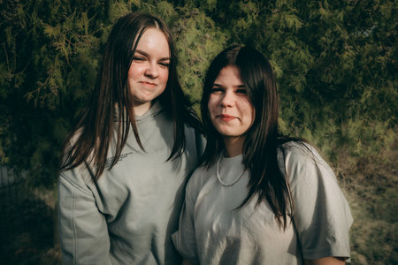 Two beautiful young women with long hair posing in the park. Toned.の写真素材