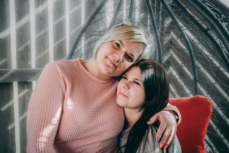 Mother and daughter sitting in a wicker chair. The concept of family relationships.の写真素材