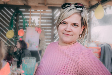 Portrait of a beautiful woman in a pink sweater at a birthday partyの写真素材