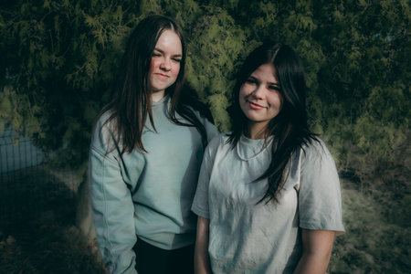 Two beautiful young women standing in the park looking at the camera.の写真素材