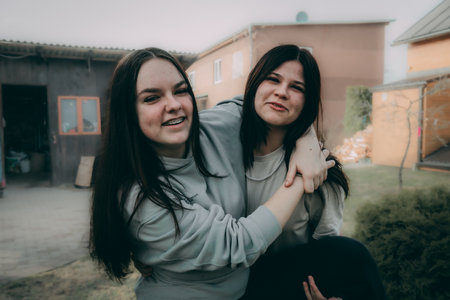 Two beautiful young women on a walk in the village. A girl with long hair and a girl in a gray hoodie.の写真素材
