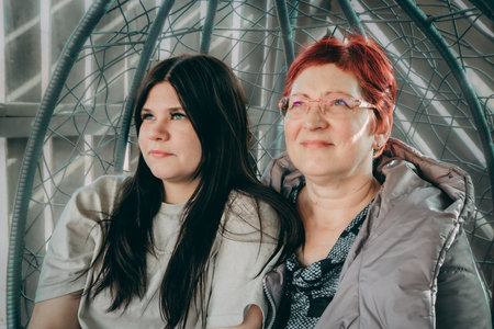 Portrait of mother and daughter sitting in a cage at home.の写真素材