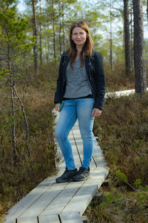 Young woman standing on a wooden boardwalk in a pine forest.の写真素材