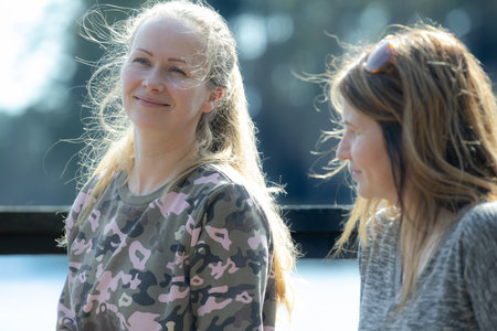 Two young women talking and smiling in the park. Close-up.の写真素材
