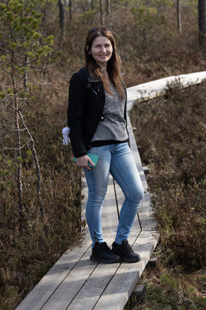 Young woman standing on a wooden boardwalk in the woods, looking at camera.の写真素材