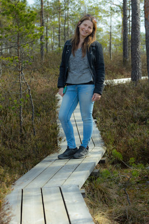 Young woman standing on a wooden boardwalk in a pine forest.の写真素材