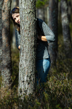 Young woman leaning against a tree in a pine forest in autumn.の写真素材