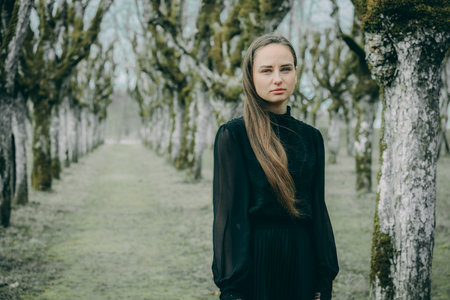 Portrait of a beautiful girl in a black dress in the spring forestの写真素材