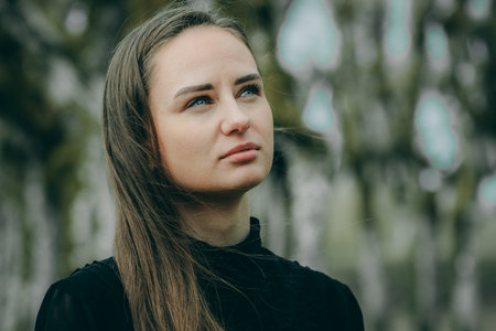 Portrait of a beautiful young girl in a black dress in the forestの写真素材