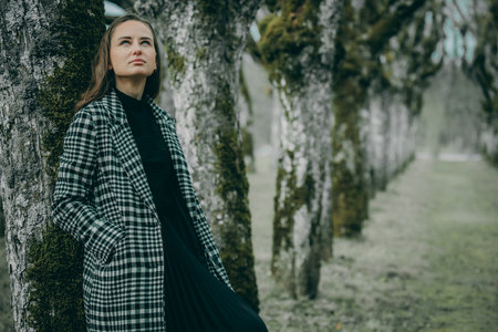 Beautiful young girl in a plaid coat in the park.の写真素材