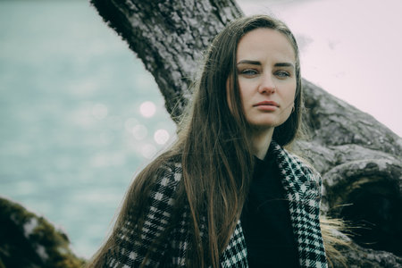 Portrait of a beautiful young woman with long hair in a plaid coatの写真素材