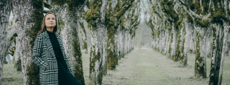 Beautiful young woman walking in a spring park. Panorama.の写真素材