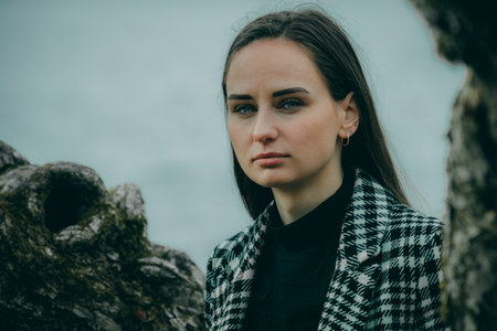 Portrait of a beautiful girl in a coat on the shore of the lakeの写真素材