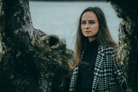 Portrait of a beautiful girl in a plaid coat on the bank of the lakeの写真素材