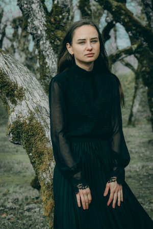 Portrait of a beautiful girl in a black dress in the forestの写真素材