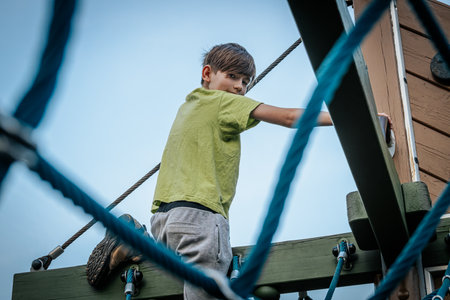 Little boy climbing on a rope bridge at the playground. Kid climbing on a rope bridge.の写真素材