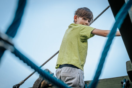 Little boy climbing on a rope bridge on a sunny summer day.の写真素材