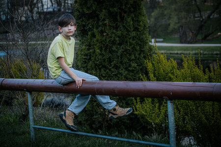 Portrait of a boy sitting on a railing in the park.の写真素材