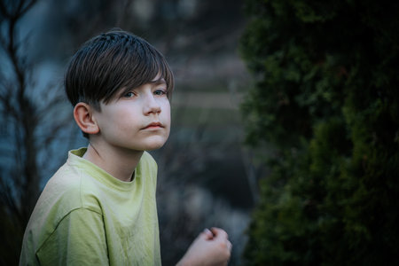 Portrait of a boy standing in the park looking at the cameraの写真素材