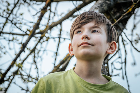 Portrait of a boy in a green t-shirt on a background of trees.の写真素材