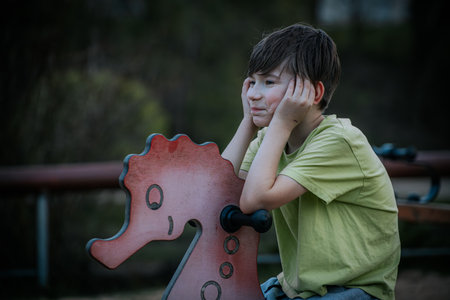 Boy sitting on a rocking horse in the park. Selective focus.の写真素材