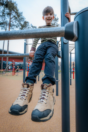 little boy doing pull ups on outdoor sports ground in autumn day.の写真素材