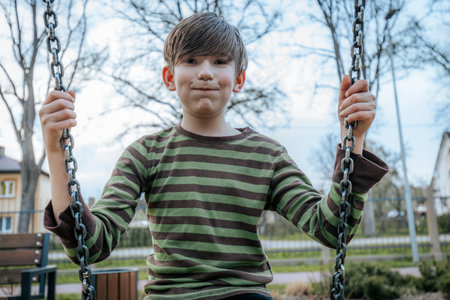 Portrait of a boy in a striped T-shirt on a swingの写真素材