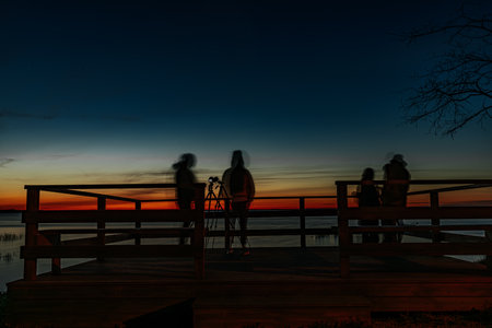 Silhouette of photographer on the pier at sunset in the eveningの写真素材