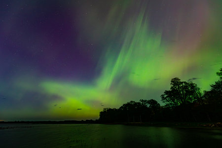 Aurora borealis in the night sky over the lake.の写真素材