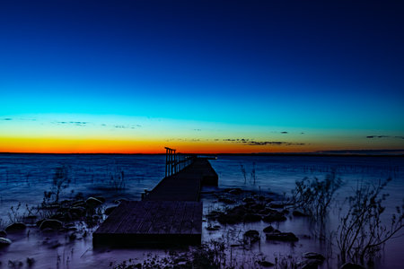 Beautiful sunset on the lake with a wooden pier and blue skyの写真素材