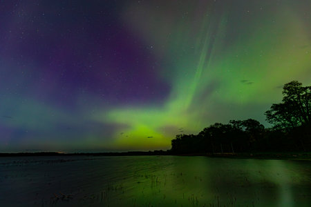 Aurora borealis in the night sky over the lake.の写真素材