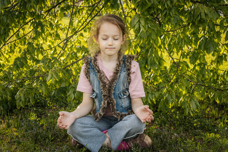 little girl meditating in the park on a sunny summer day.の写真素材
