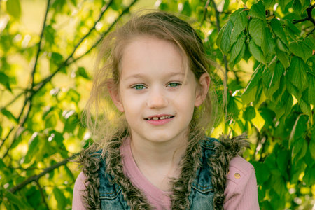 Portrait of a little girl on a background of green foliage.の写真素材