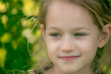 Portrait of a beautiful little girl with green eyes in the parkの写真素材