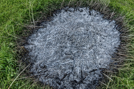 A close-up view of a pile of ashes, remnants of a fire, with intricate textures and tones, representing transformation and renewal.の写真素材