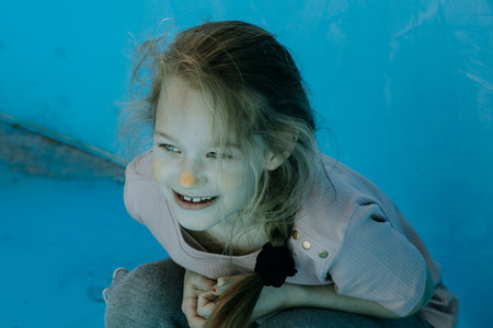 Portrait of a little girl with long hair on a blue backgroundの写真素材