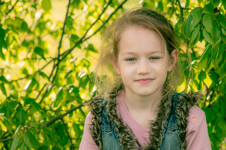 Portrait of a little girl on a background of green foliage.の写真素材