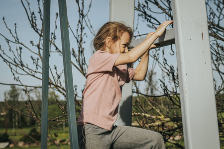 little girl playing on a swing in the garden on a sunny dayの写真素材