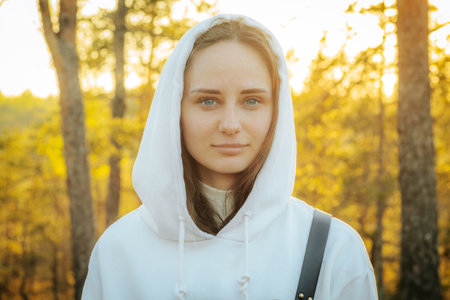 Portrait of a girl in a white sweatshirt in the autumn forestの写真素材