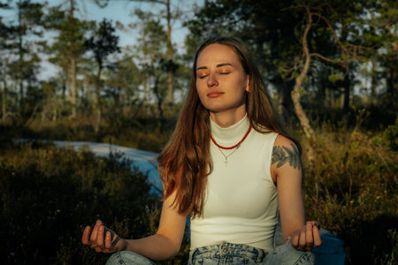 Young woman meditating in the forest. Yoga and meditation concept.の写真素材