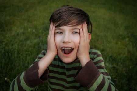 Portrait of a boy with his hands on his face. The boy is surprised.の写真素材